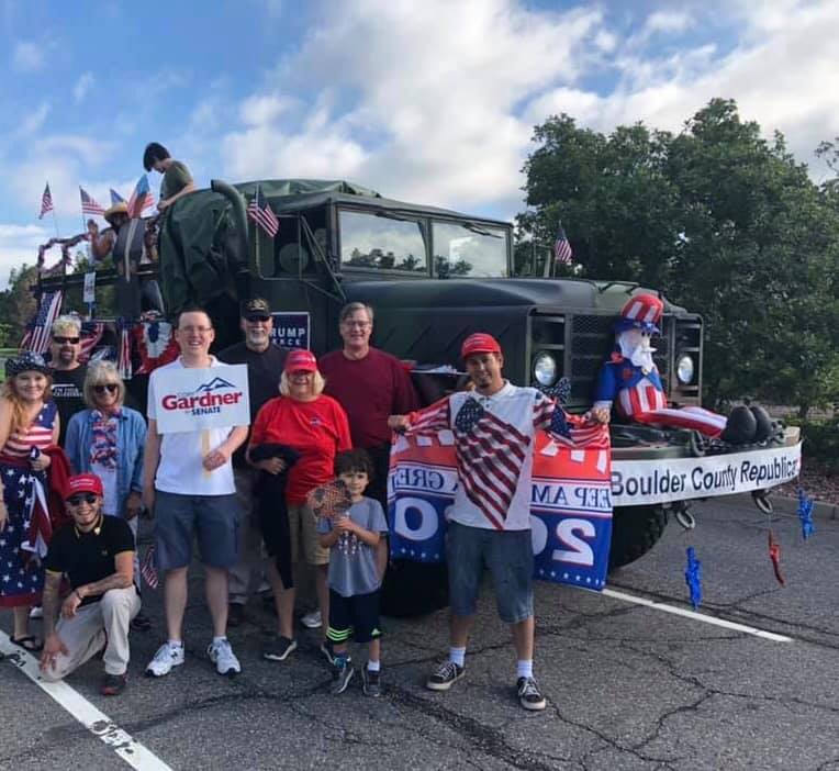 A group of people standing in front of a truck. Some of them are wearing Trump hats.